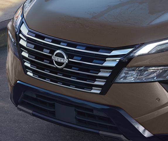 2024 Nissan Rogue showing bold v-motion grille, parked on a suburban street