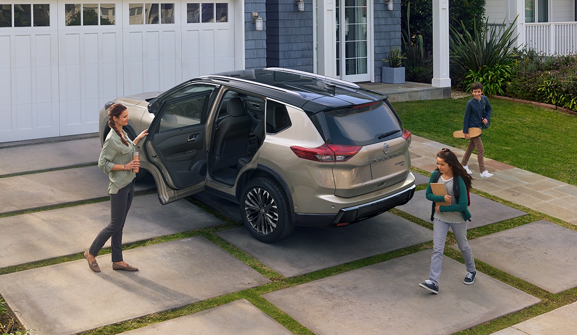 2024 Nissan Rogue parked in a driveway, with a woman opening the rear door