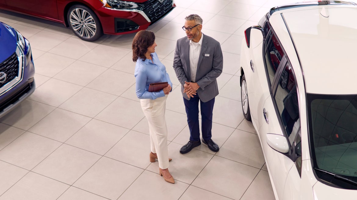 Two people at Nissan dealership discussing Business Fleet offers and financing