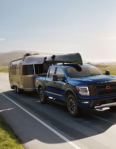 2024 Nissan TITAN on highway with canoe on top and towing an airstream illustrating towing capability