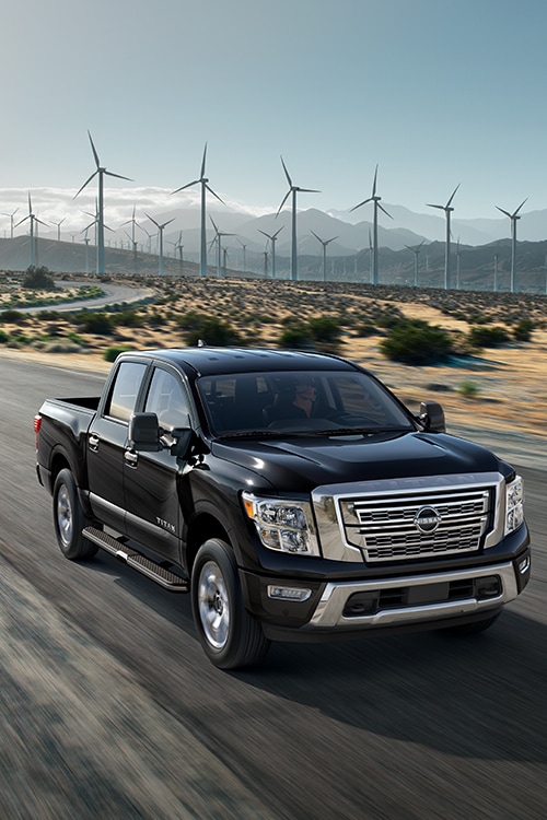 2024 Nissan TITAN in black on highway with wind turbines in the background
