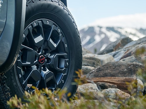 2024 Nissan Frontier detail view of front wheel with mountains in the background