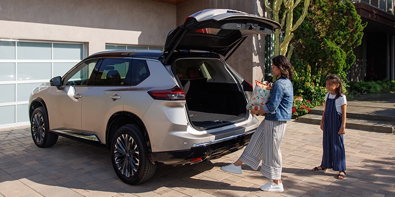 2024 Nissan Rogue parked lakeside, with rear liftgate opened and cargo visible inside