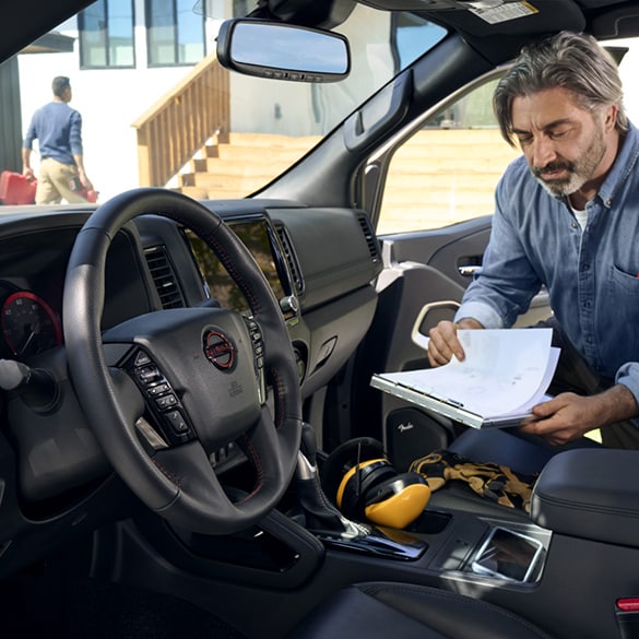 Man reviewing a business fleet manual guide inside a Nissan vehicle