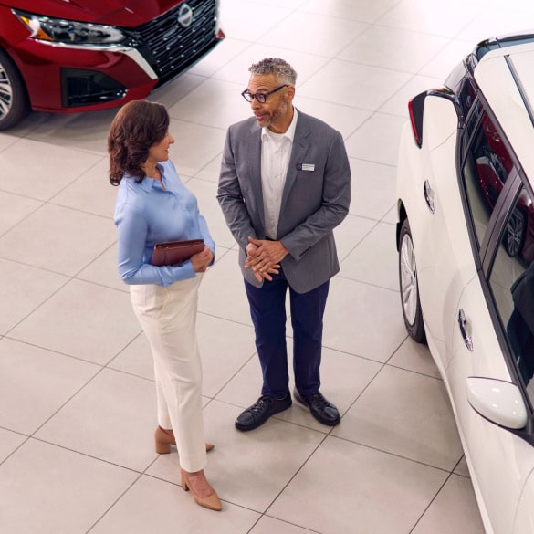 Two people at Nissan dealership discussing Business Fleet offers and incentives