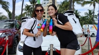 Two people celebrating nissan pride in miami holding nissan water bottles