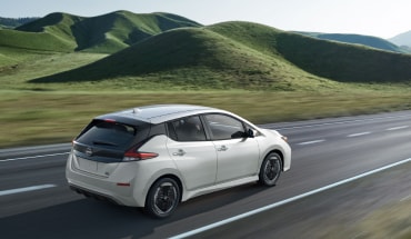2023 white Nissan LEAF driving through scenic road.
