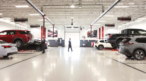 Spacious garage with multiple Nissan vehicles parked.