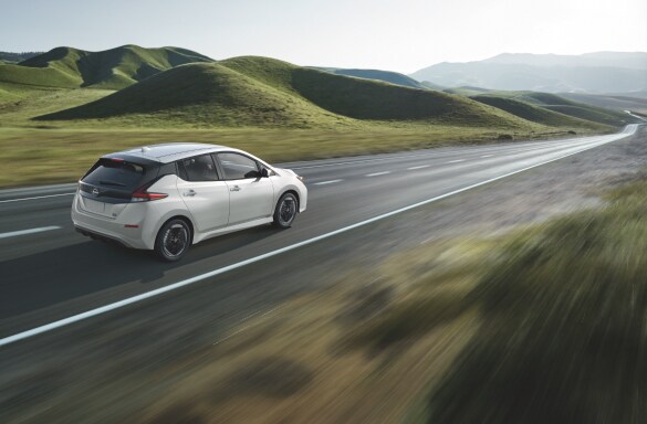 Eco-friendly Nissan Leaf on a lush highway.