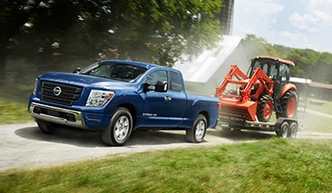 2021 Nissan TITAN towing a front end loader on a trailer
