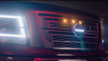 Nissan TITAN closeup of headlights on at night and illuminated center badge