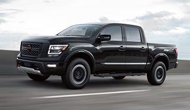2023 Nissan TITAN PRO-4X in black on a highway to illustrate driver assist and safety technology sensors.