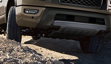 2023 Nissan TITAN showing front tires climbing rough terrain illustrating ground clearance.
