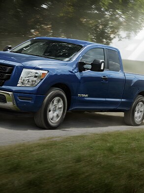 2023 Nissan TITAN king cab in blue driving through the country.