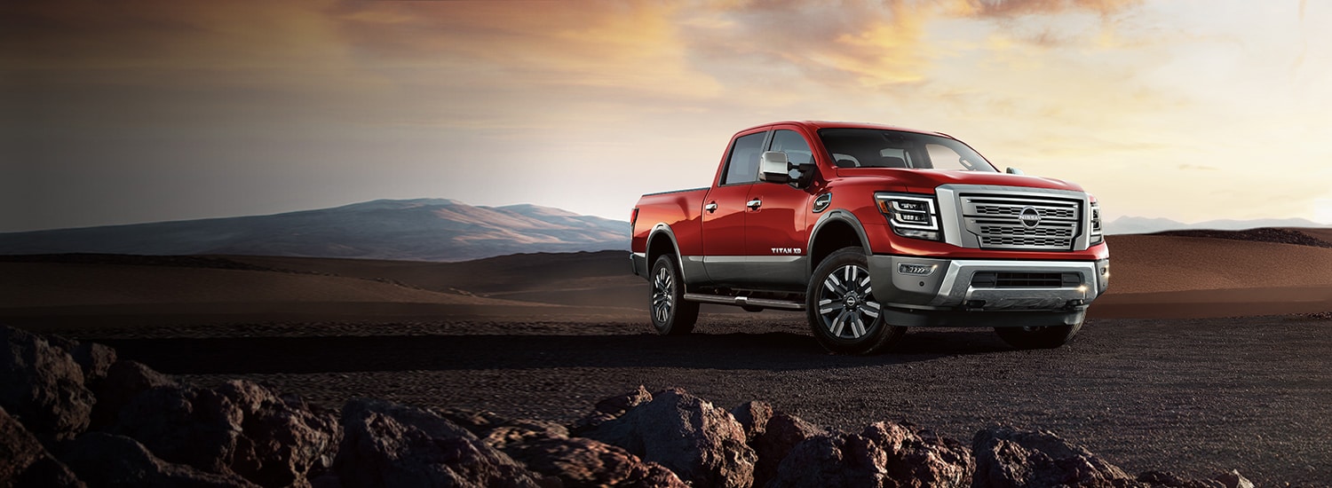 2023 Nissan TITAN Crew Cab in red parked on hill off-road at sunset.
