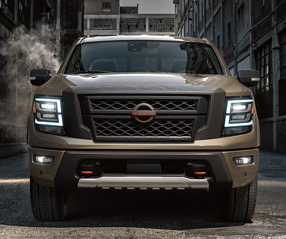 2024 Nissan TITAN in Baja Storm front view in an alley displaying front end grille