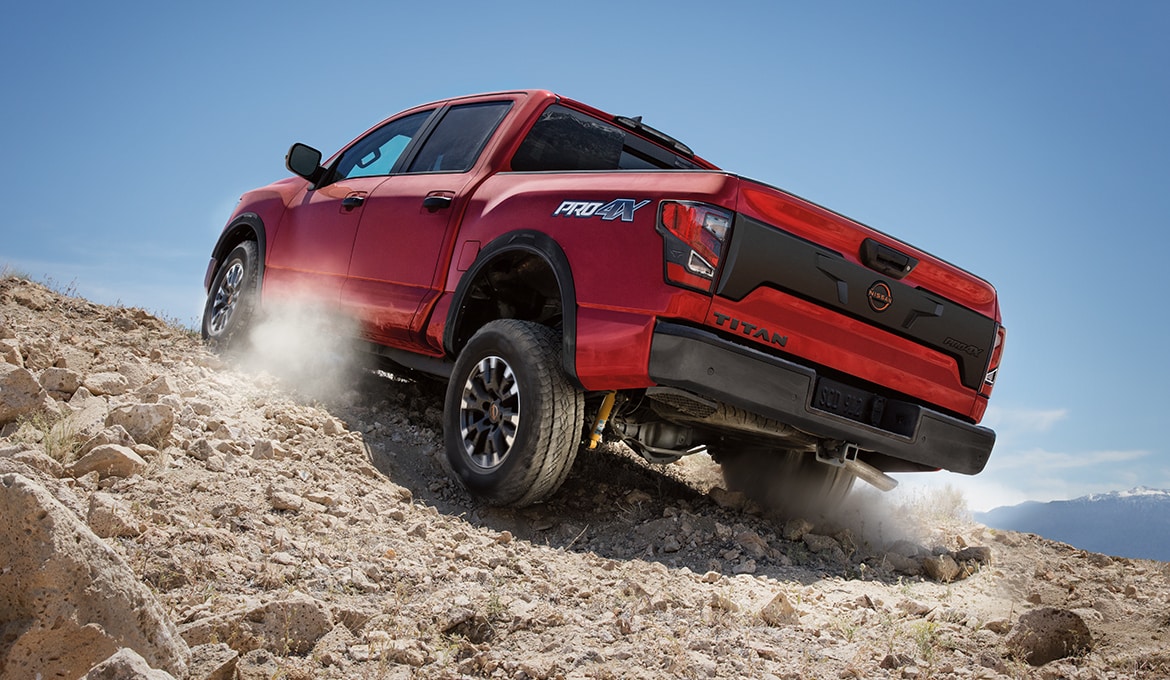 2024 Nissan TITAN in red climbing a large rock pile illustrating horsepower off-road