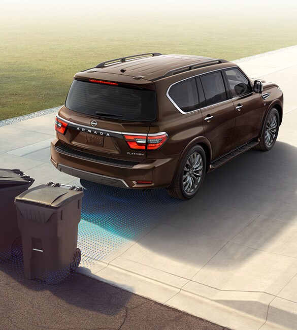 2022 Nissan Armada backing into a driveway showing safety shield 360 sensors detecting trash cans behind it.