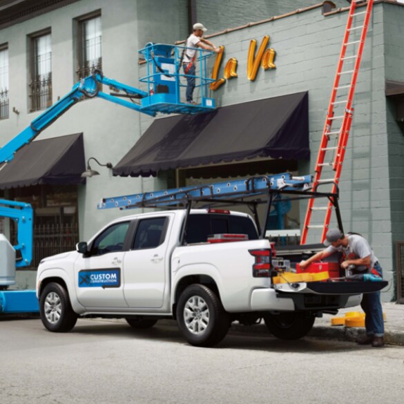 2022 Nissan Frontier bed with tailgate open with man unloading construction materials.