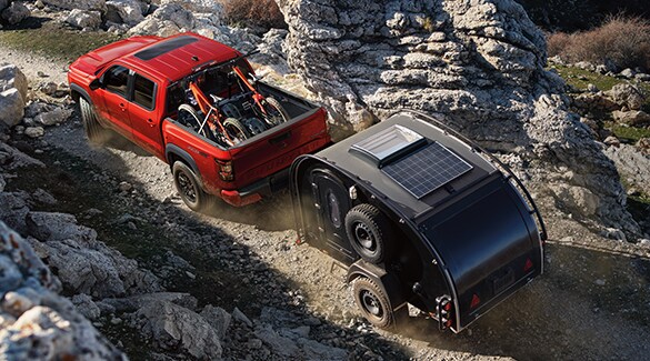 2022 Nissan Frontier off-road using around view monitor to navigate narrow rock passage towing a camper.