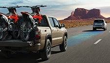 2023 Nissan Frontier on highway in the mountains carrying motorcycles.