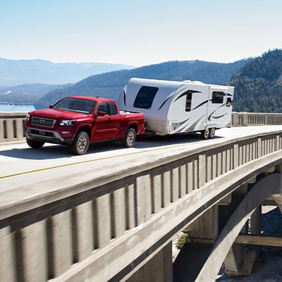 2024 Nissan Frontier driving across a bridge while towing an RV