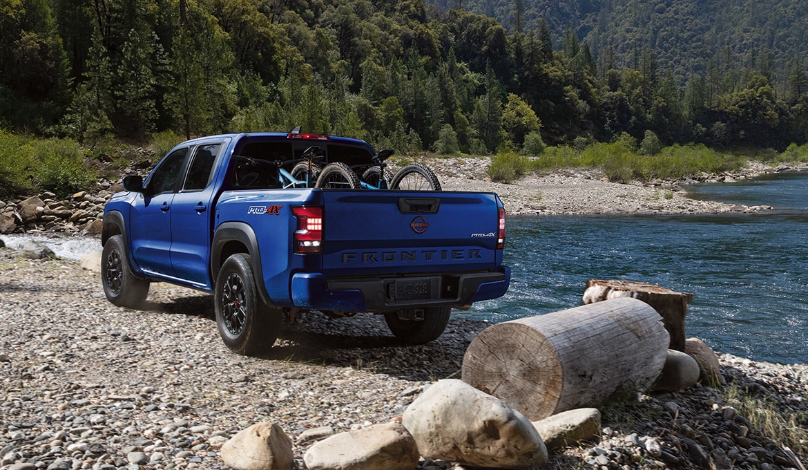 2024 Nissan Frontier parked on a lake shore with two bicycles in the bed