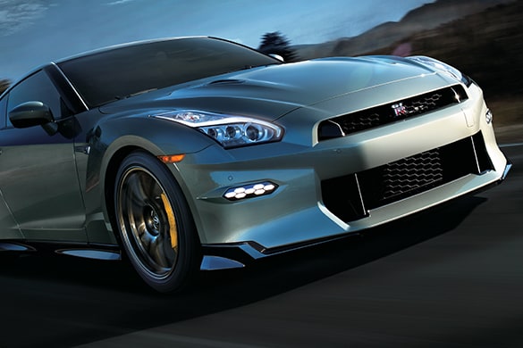 2024 Nissan GT-R in Millennium Jade driving down a road at speed, front view.