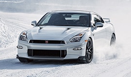 2024 Nissan GT-R driving around a curve in the snow.