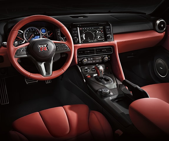 2024 Nissan GT-R interior view showing leather-wrapped steering wheel and leather seats.