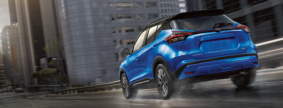 2023 Nissan Kicks in blue driving on wet city streets illustrating performance
