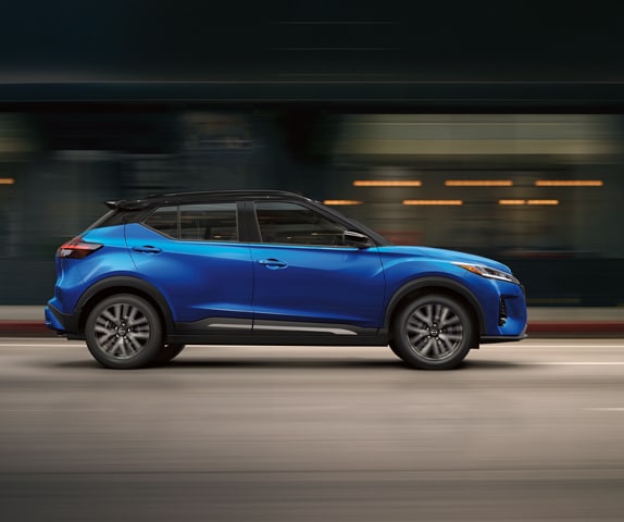 2024 Nissan Kicks in profile driving on a downtown street