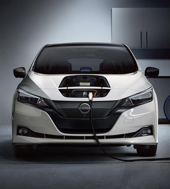 2023 Nissan LEAF front view in white with charger hatch open and connected to charging station