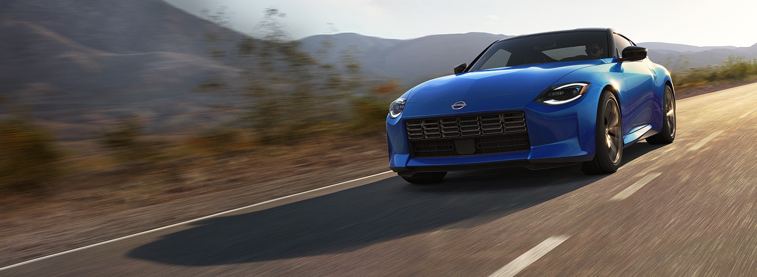 2023 Nissan Z in blue driving on a rural road at speed.