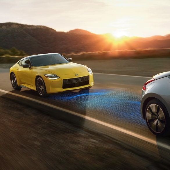 2024 Nissan Z in yellow driving down a rural highway with the sun rising in the background