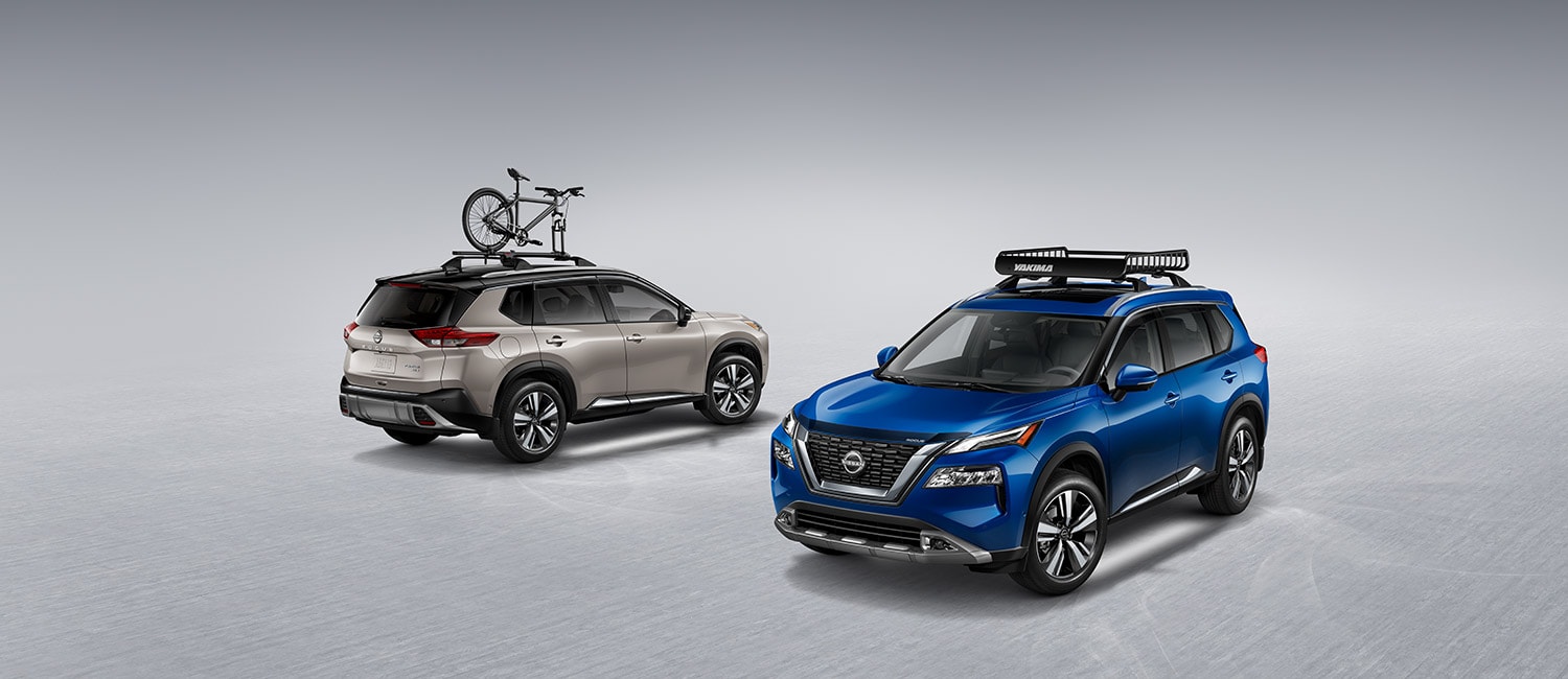 2022 Nissan Rogue with roof racks and exterior ground lighting on gray background.