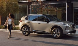 2023 Nissan Rogue in two-tone champagne silver metallic and super black parked on a city street.