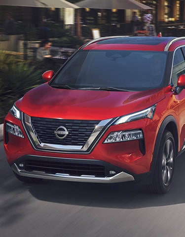 2023 Nissan Rogue in red driving in the city