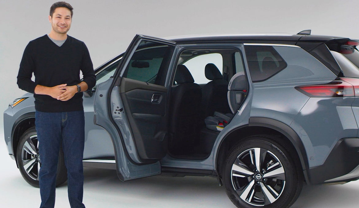 Auto expert standing beside 2023 Nissan Rogue with open door, ready to explain car features