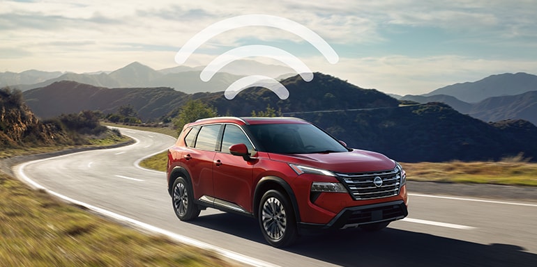 2024 Nissan Rogue driving down a mountain road, with a WiFi logo overhead