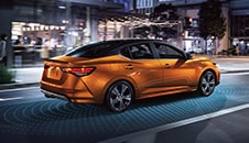 2022 Nissan Sentra at night driving with illustration of driver assist technology sensors.