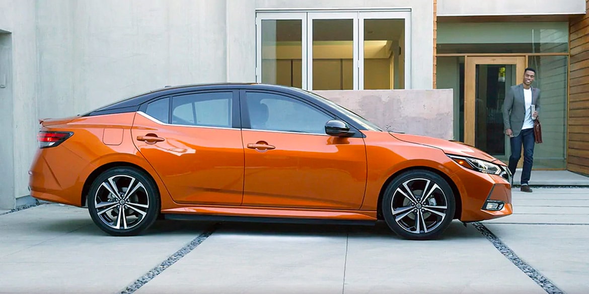 2022 Nissan Sentra in Two-tone Monarch Orange Metallic / Super Black parked in driveway with person walking toward it.