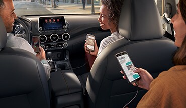 2023 Nissan Sentra interior with people using their smartphones to show device connectivity.