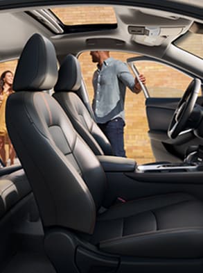 2023 Nissan Sentra seen premium interior from the passenger side with people about to get in driver's side front and rear.