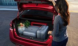 2023 Nissan Versa showing a person closing the trunk with luggage and groceries inside.